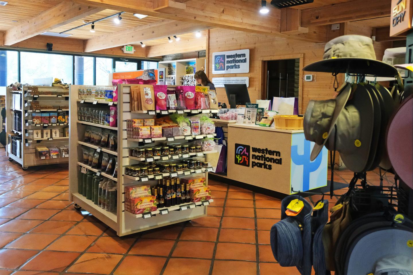 Shop interior with merchandise displays and hatted mannequin near a checkout counter.