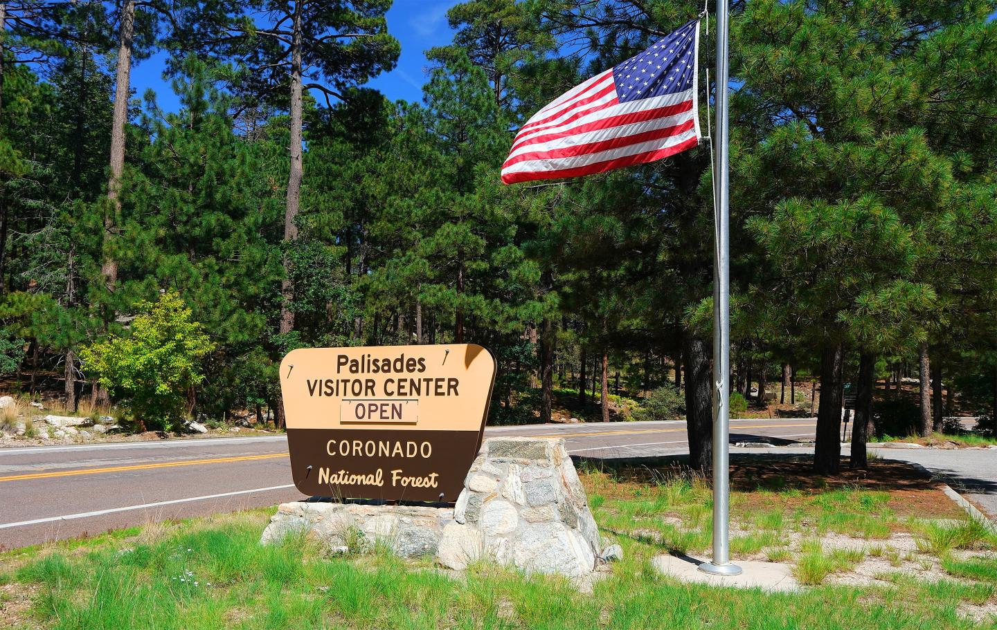 Visitor center sign and American flag in forest setting.