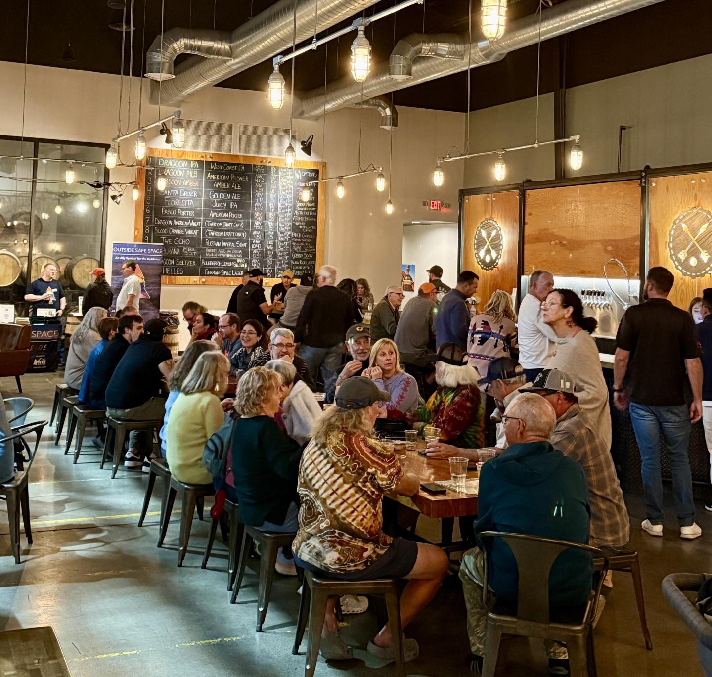 Dragoon Brewery with people socializing at tables, warm lighting above.