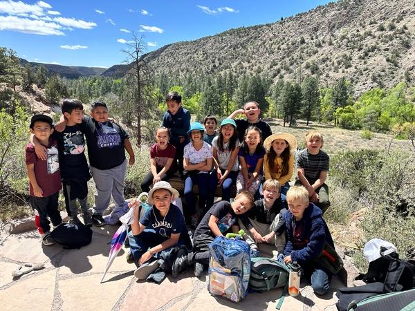 Group of children smiling outdoors with mountains in the background.