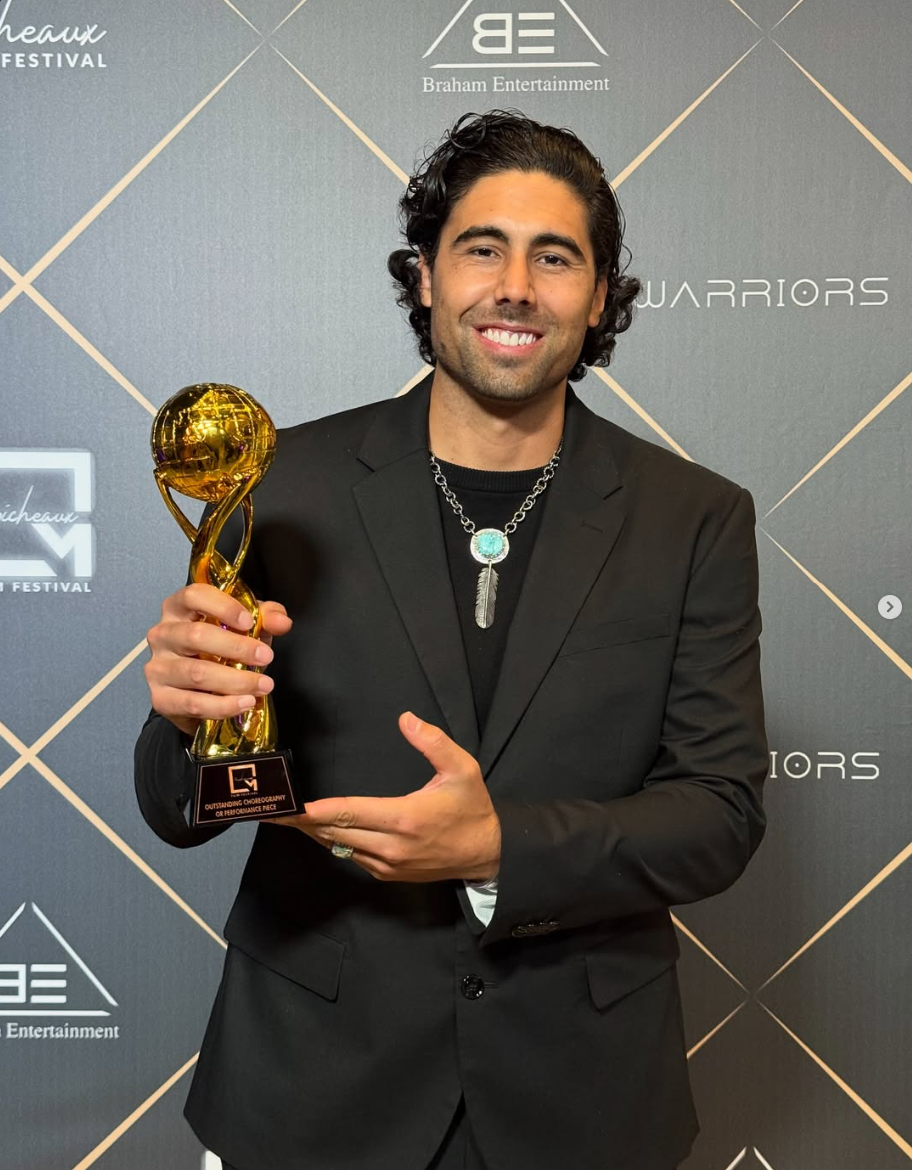 Eric Michael Hernandez holding a golden trophy, smiling.