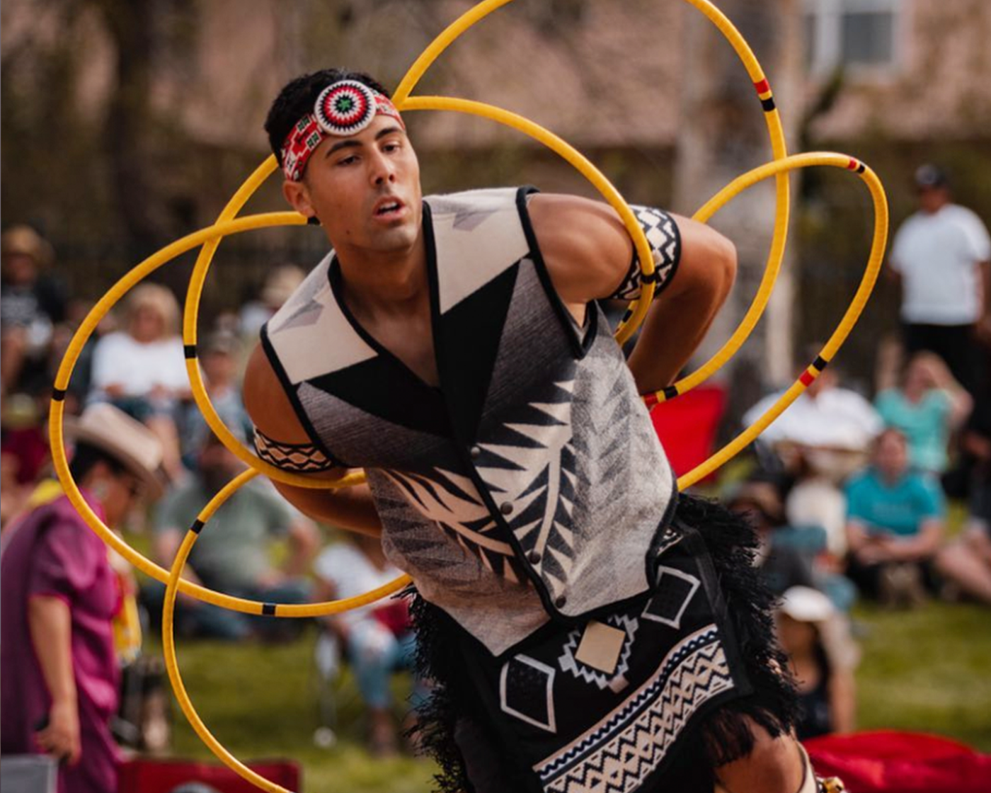 Traditional dancer performs with hoops at an outdoor event.