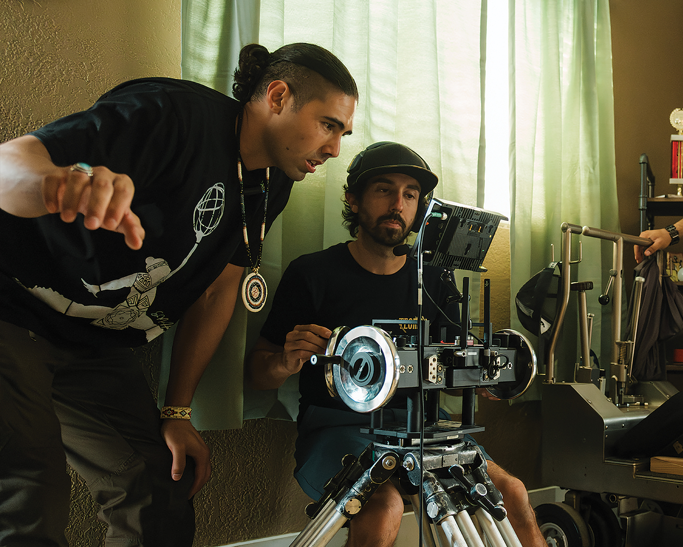 Film crew members adjusting camera equipment indoors.