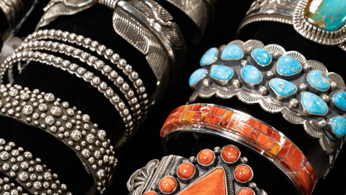 Silver and turquoise bracelets with intricate designs displayed on black velvet.