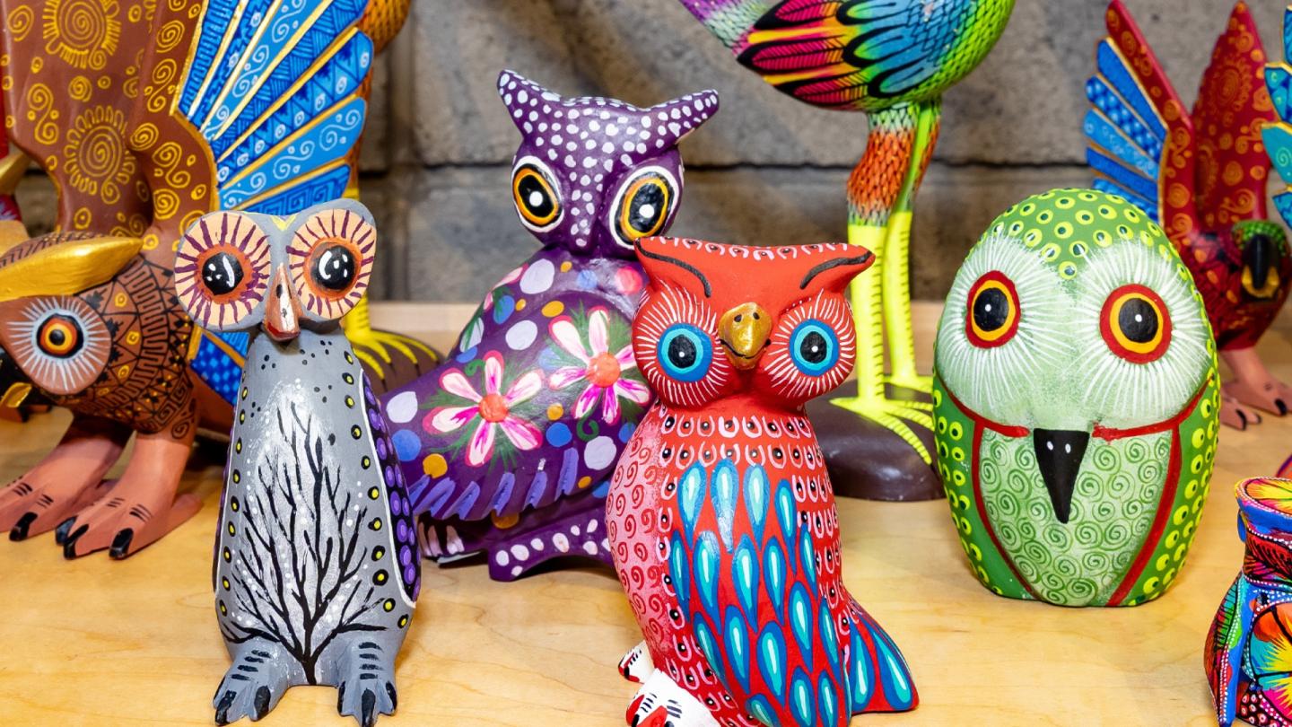 Colorful painted owl figurines on display.