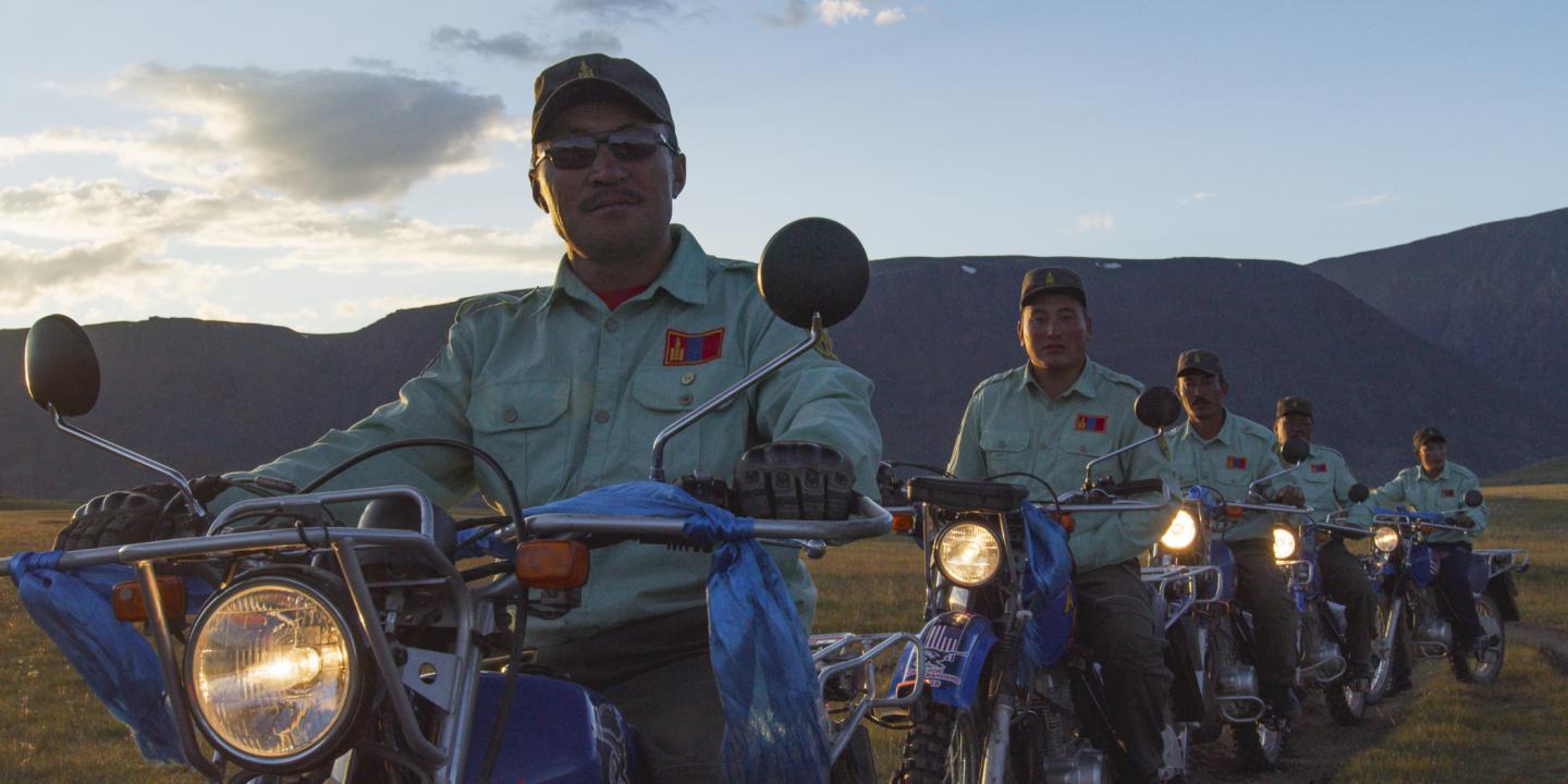 Group of people on motorcycles in the countryside at sunset.
