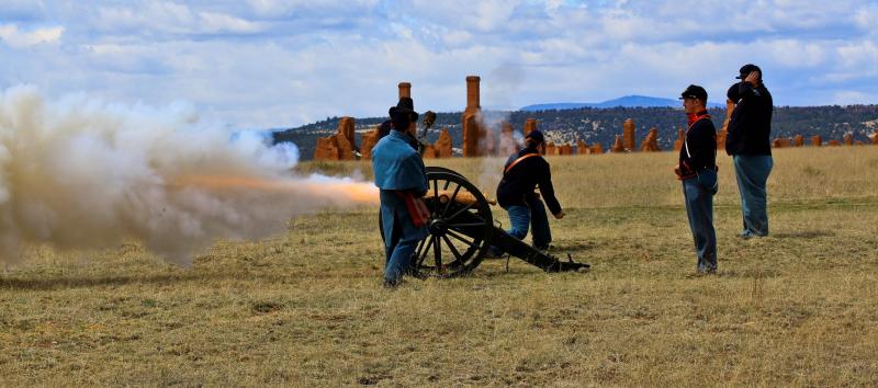 Uniformed living history interpreters firing a cannon.