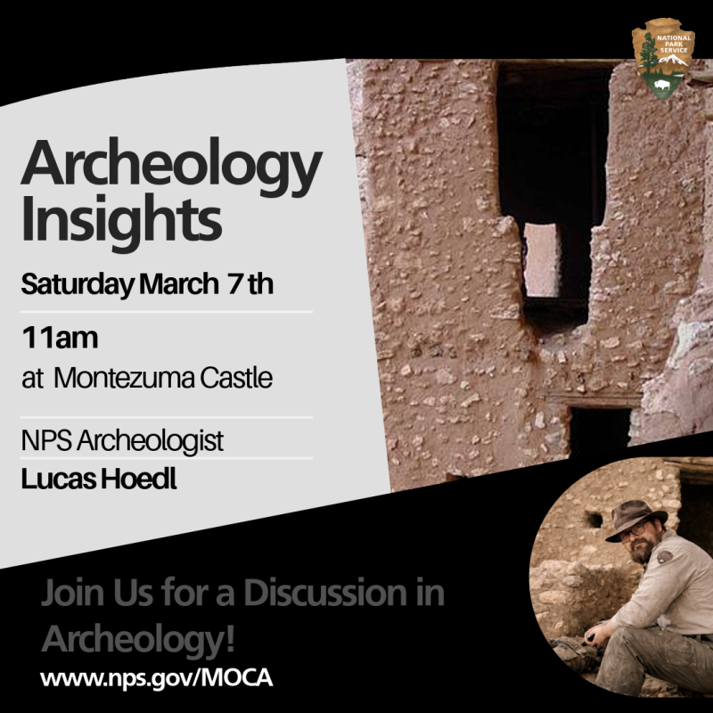 An archeologist sits in front of a cliff dwelling