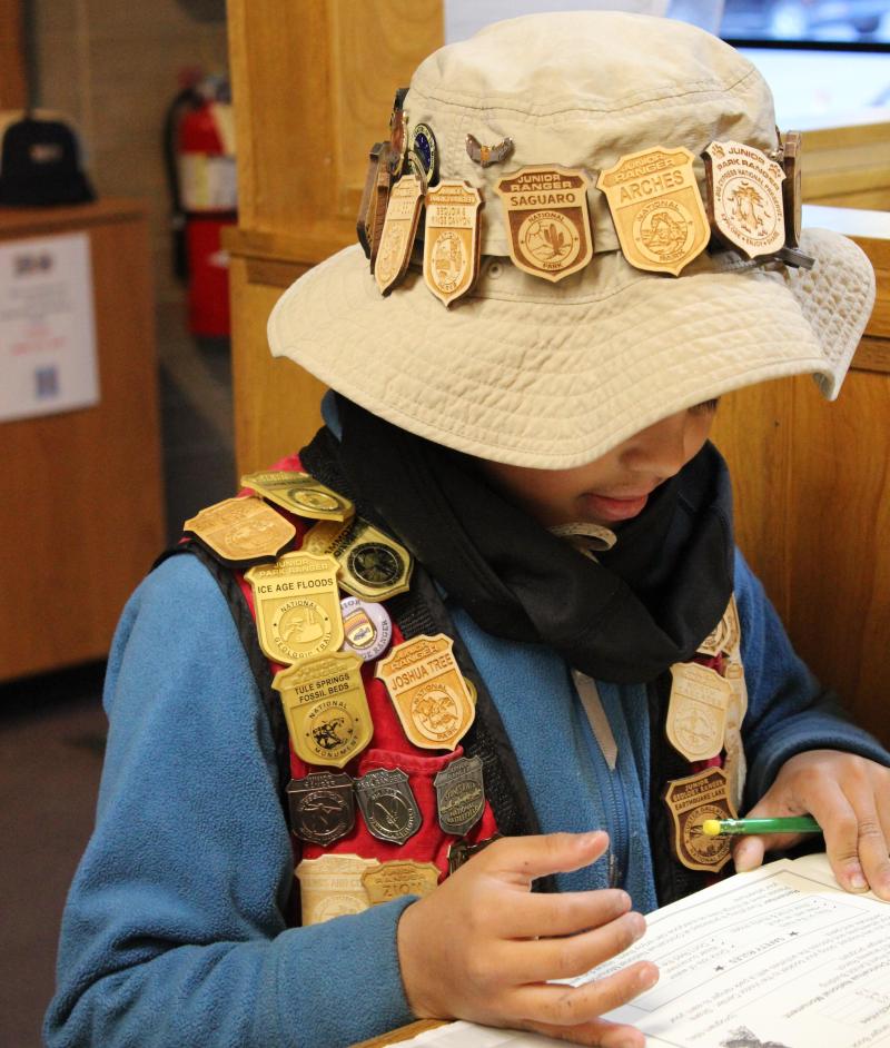junior ranger with many badges on hat and vest