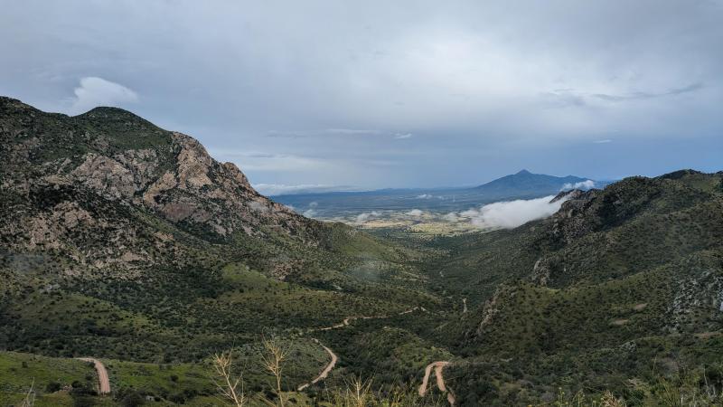 A view from Montezuma Pass Overlook looking east toward a cloudy and rainy San Pedro River Valley.