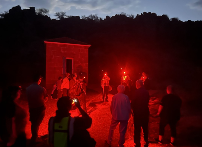 Tour group being led by red light headlamps on night hike at Fort Davis National Historic Site.