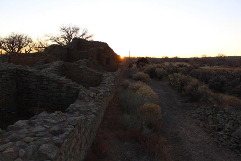 The sun setting along a sandstone wall.