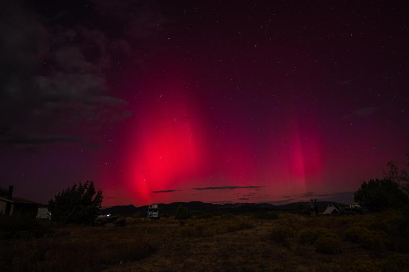 A colorful band of pinkish red light shines in the night sky