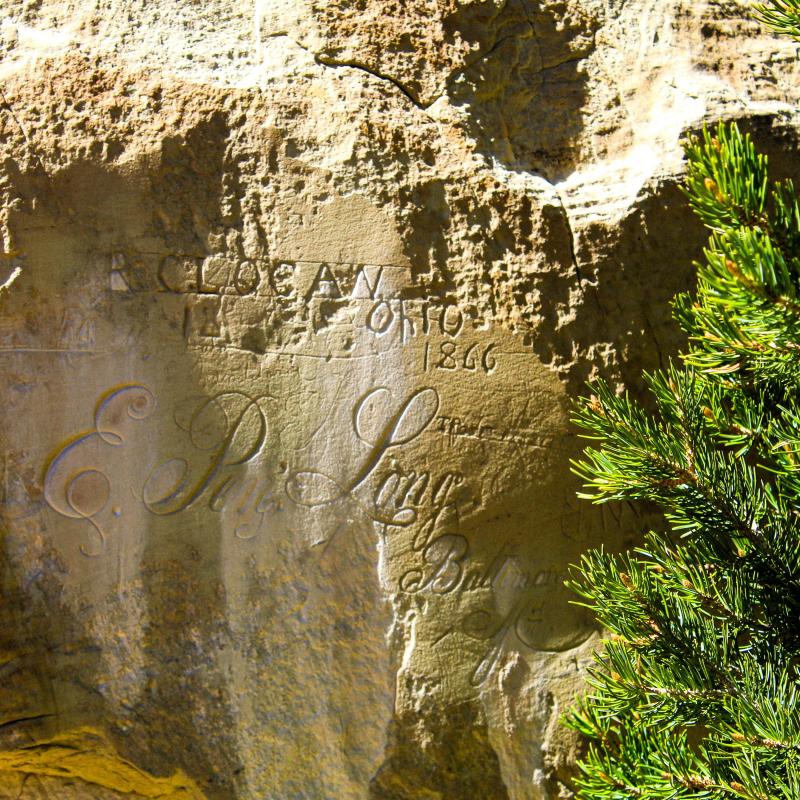 Historic rock face with carved inscriptions, including the name “E.P. Long"