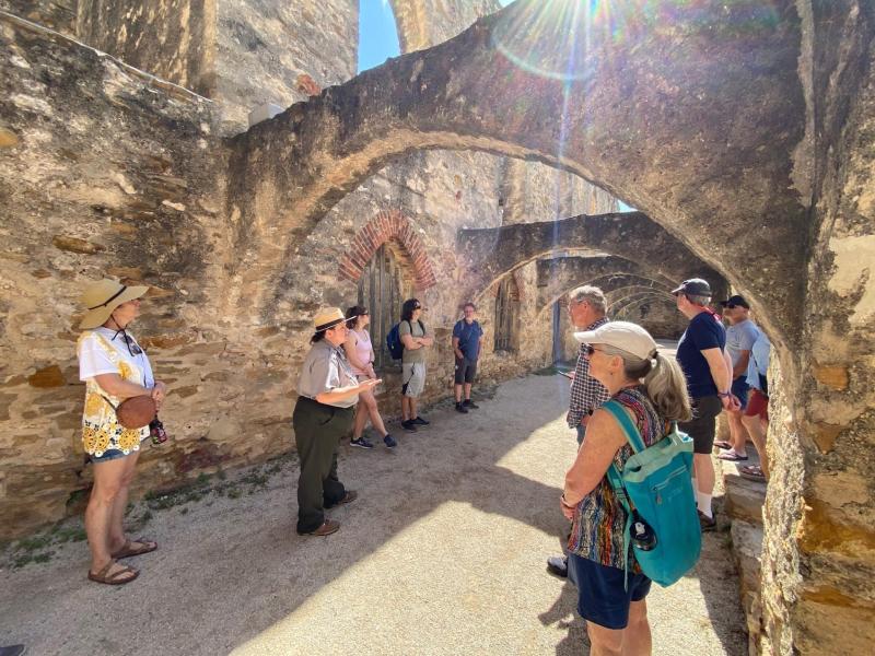 Park Ranger giving a tour to a group of people under stone arches