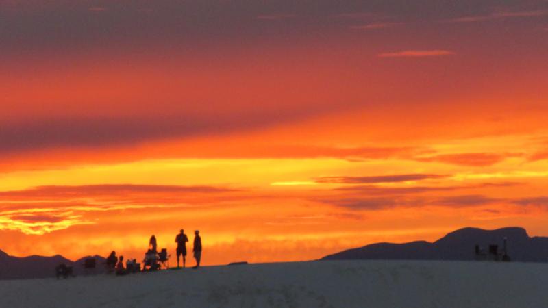 people silhouetted against a sunset sky