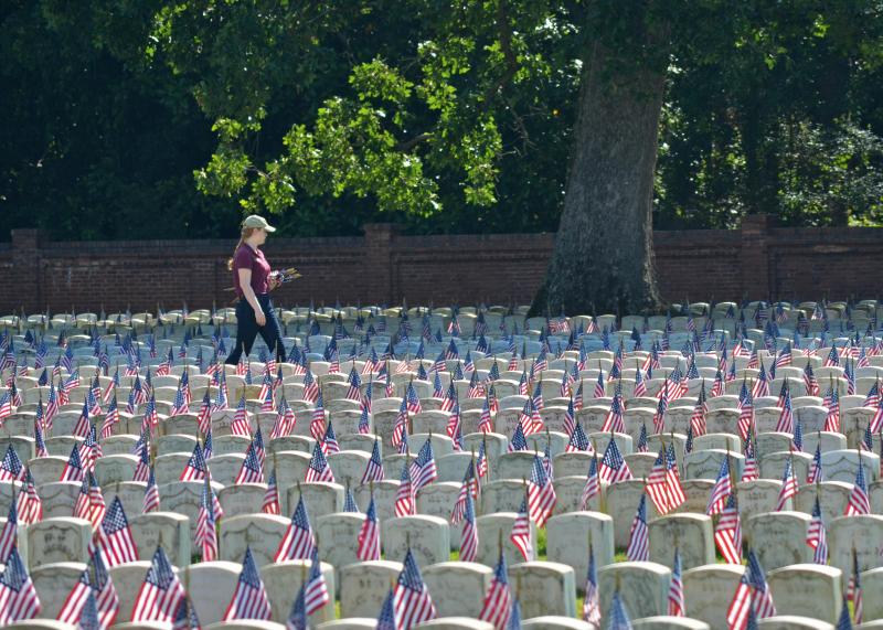 A park volunteer straightens flags in a Civil War section of Andersonville National Cemetery