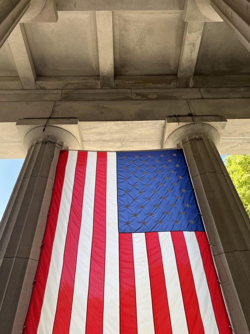 American flag hanging down between two columns