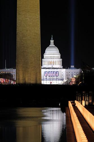 Reflecting pool lined with lanterns at night. The Washington Monument, US Capitol building, and spot