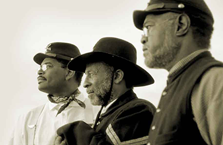 Sepia toned photo of three Black men in historic military uniforms in profile