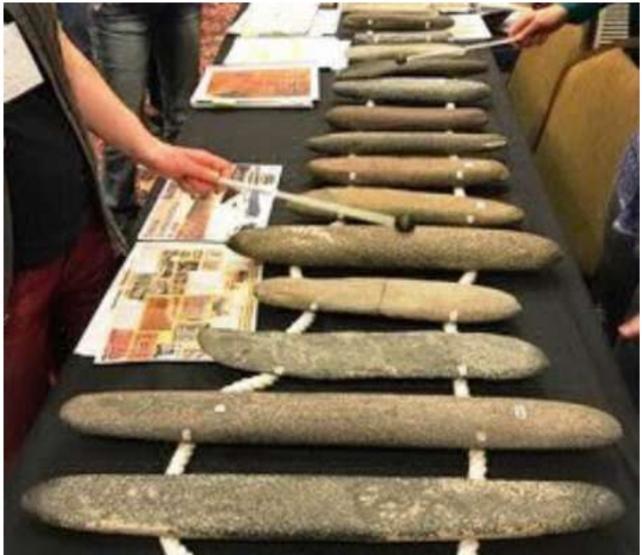 A series of elongated stones laying on a table in a set up that resembles an xylophone