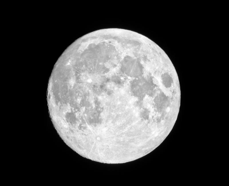 The full Moon as seen through a telescope, showing its dark and light colored regions.
