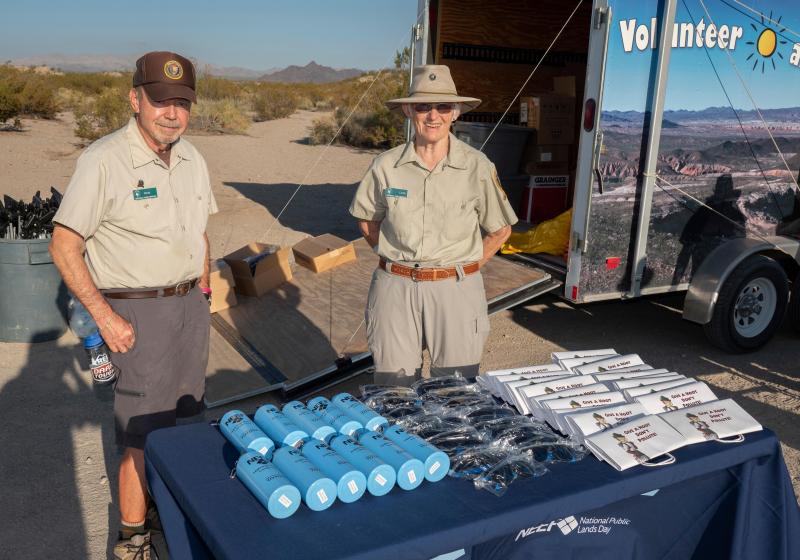 Volunteers stand next to a table display