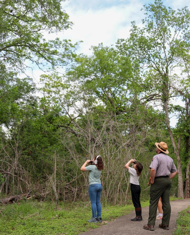 ranger looking at wildlife with two girls on a trail