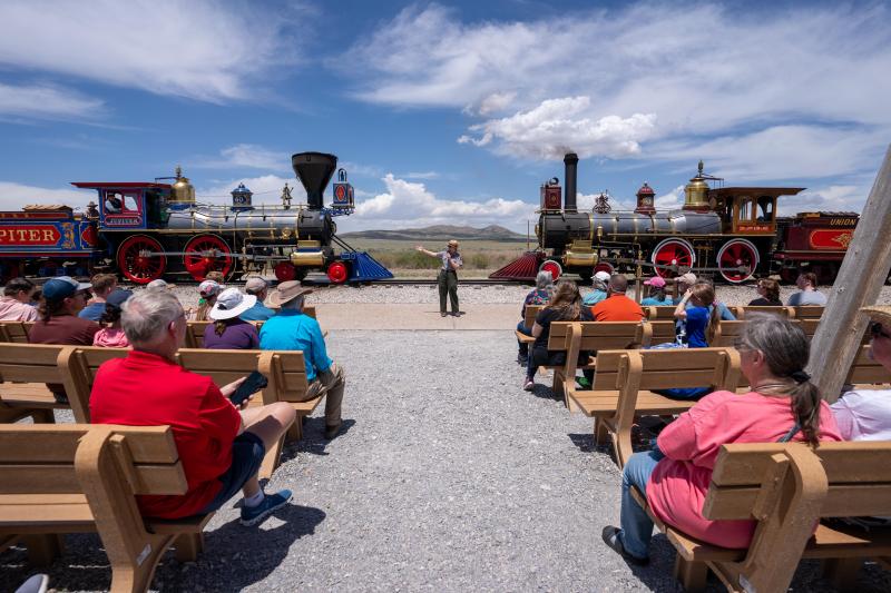 Ranger giving a program Infront of two historic Victorian steam locomotives