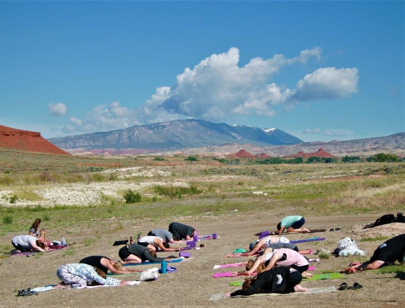A group of people doing yoga with mountains in the background.