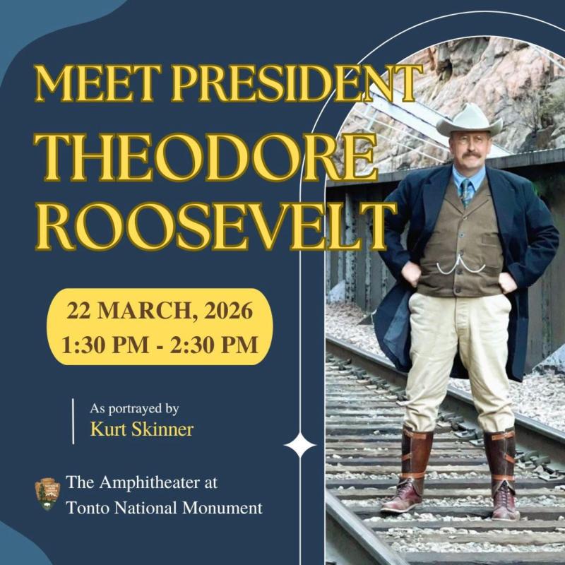 a man portraying President Theodore Roosevelt stand on railroad tracks with hand on hips.