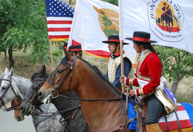 A group of young people on horseback holding different flags