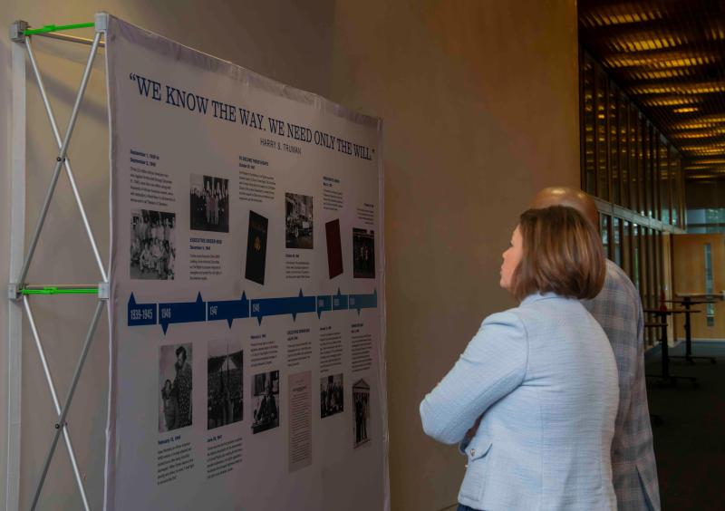 Two African American people read the timeline of President Harry S. Truman's work in civil rights.