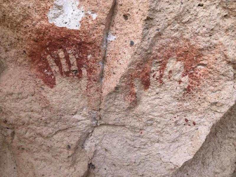 red negative handprints on a pink cliff face