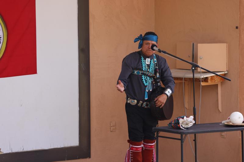 A man in traditional Navajo regalia speaking into a microphone