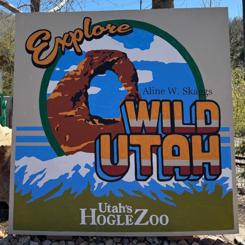 A painted wooden sign with a rock arch that says "Explore Wild Utah".