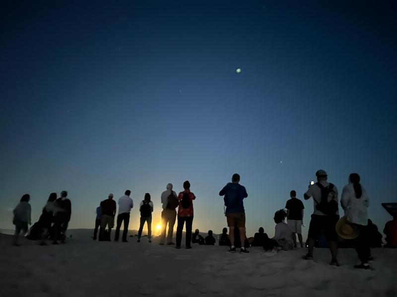 A group of people watch the moon rise