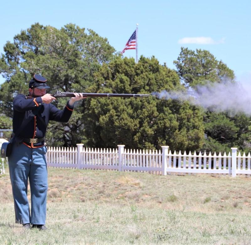 A uniformed living history interpreter demonstrating a black powder weapon.
