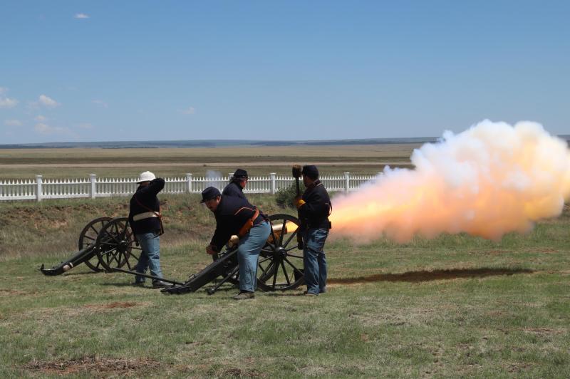 Uniformed living history demonstrators firing a cannon.
