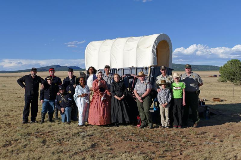 A group of living history interpreters and ranger staff with a covered wagon.