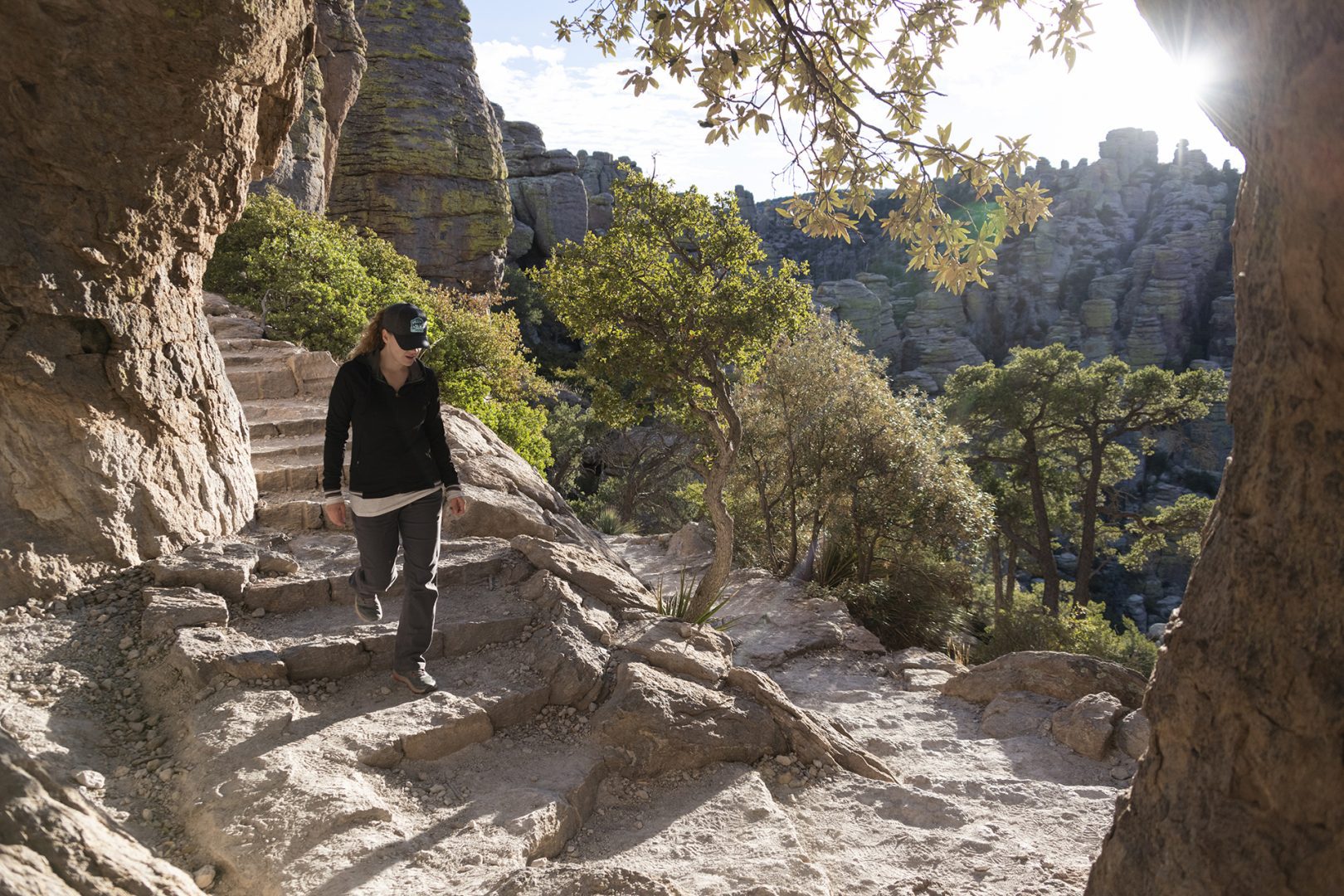 Hiker descends stone steps at Chiricahua National Monument with sunny sky in the background